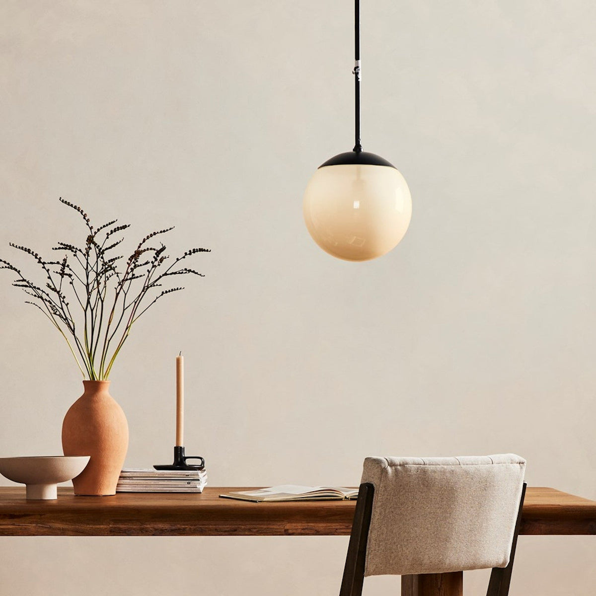 Sutton Small Pendant illuminated, showing the frosted glass globe and black stem